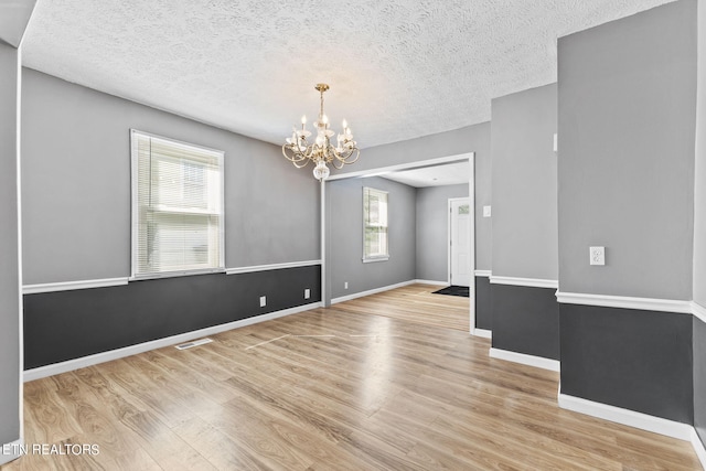 spare room with light hardwood / wood-style floors and a textured ceiling