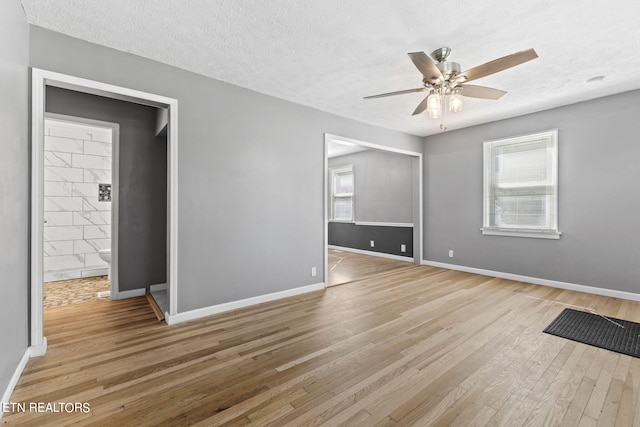 unfurnished bedroom with ceiling fan, a textured ceiling, light wood-type flooring, and ensuite bathroom