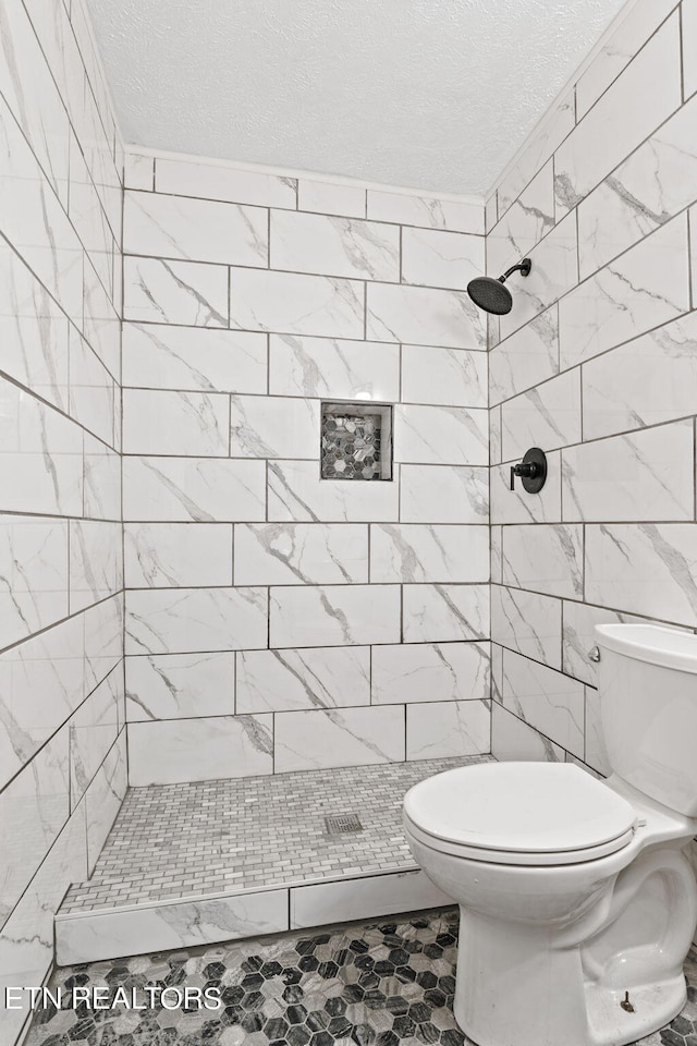 bathroom with tile flooring, a textured ceiling, a tile shower, tile walls, and toilet