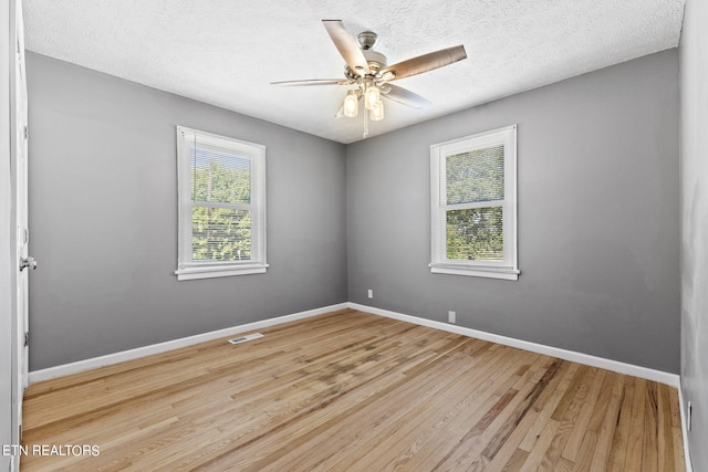 unfurnished room featuring ceiling fan, plenty of natural light, light hardwood / wood-style floors, and a textured ceiling