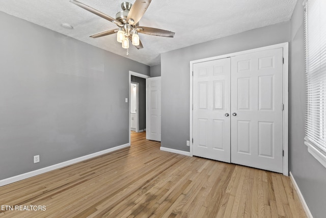 unfurnished bedroom featuring a closet, ceiling fan, light hardwood / wood-style floors, and a textured ceiling