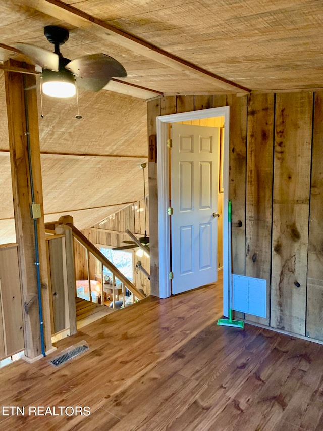 interior space featuring wooden walls, wood-type flooring, and ceiling fan