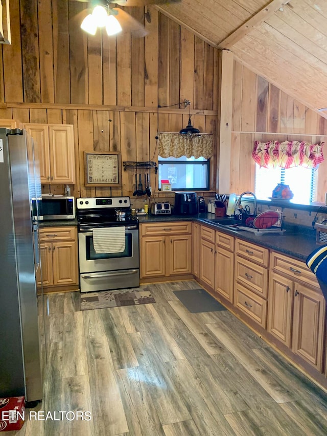 kitchen with appliances with stainless steel finishes, wood-type flooring, wooden walls, lofted ceiling, and wooden ceiling