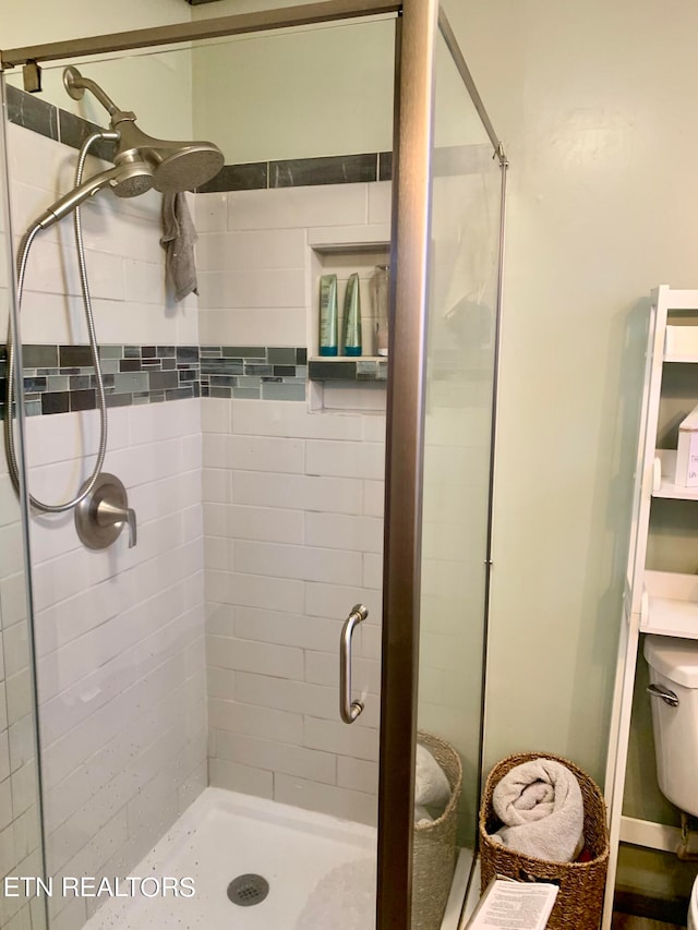 bathroom with a shower with door and toilet