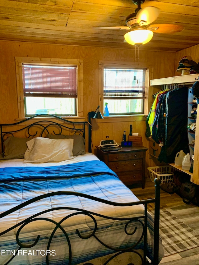 bedroom with wooden walls, ceiling fan, wood ceiling, and wood-type flooring