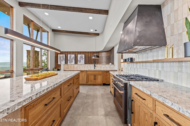 kitchen with decorative light fixtures, light tile flooring, stainless steel stove, backsplash, and wall chimney range hood