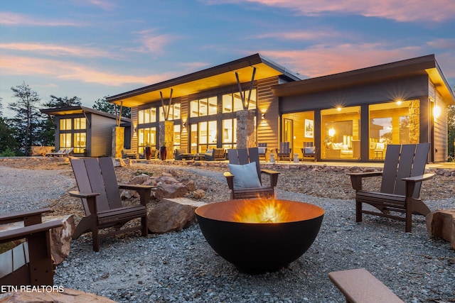 back house at dusk featuring a patio and a fire pit