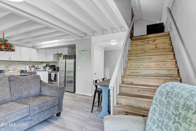 living room with beamed ceiling, light hardwood / wood-style floors, and sink