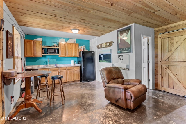 kitchen with a barn door, black appliances, wood ceiling, and concrete flooring