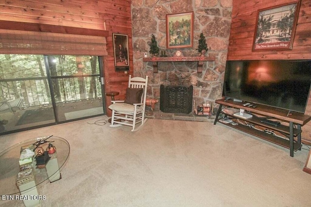 carpeted living room featuring wood walls and a stone fireplace