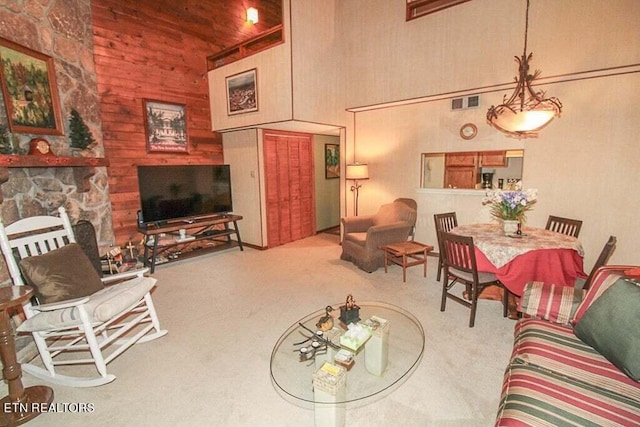 carpeted living room with wooden walls, a high ceiling, and a fireplace