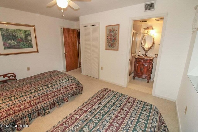 carpeted bedroom featuring ensuite bath, ceiling fan, and a closet