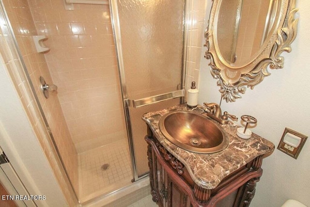 bathroom featuring tile flooring, vanity with extensive cabinet space, and a shower with shower door