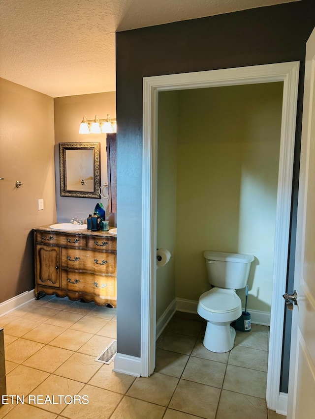 bathroom featuring toilet, tile patterned flooring, a textured ceiling, and vanity