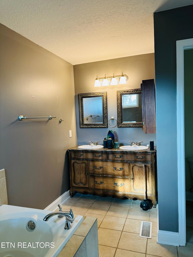 bathroom featuring a tub to relax in, tile patterned flooring, and a textured ceiling