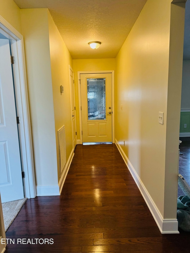 hallway featuring dark hardwood / wood-style floors and a textured ceiling