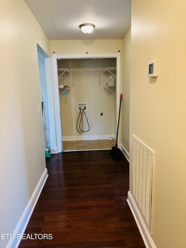 clothes washing area with dark hardwood / wood-style floors, washer hookup, and a textured ceiling