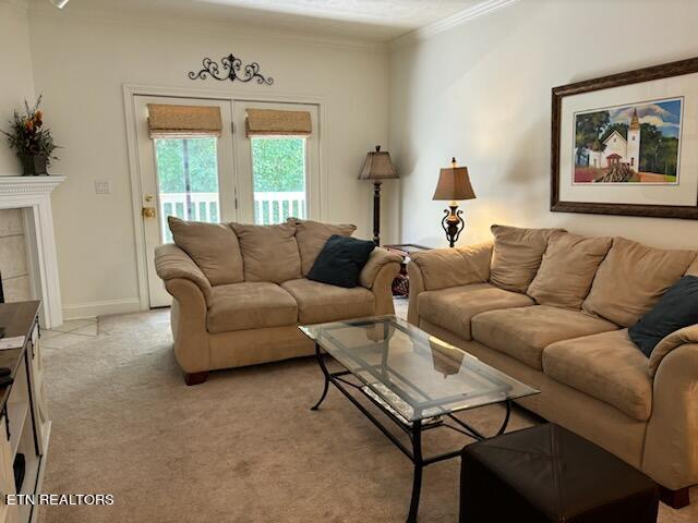 carpeted living room featuring a tile fireplace and crown molding