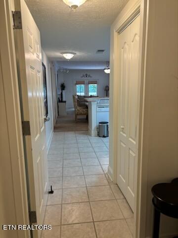 corridor with a textured ceiling and light tile patterned floors