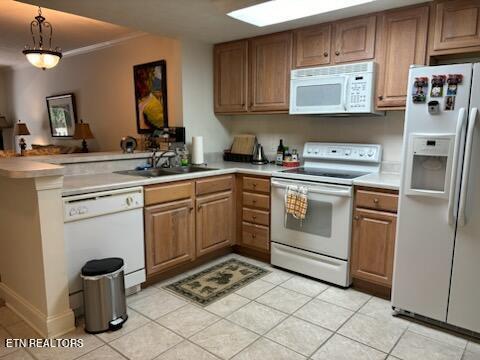 kitchen with kitchen peninsula, decorative light fixtures, white appliances, crown molding, and sink