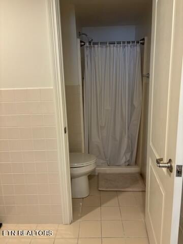 bathroom featuring toilet, tile walls, tile patterned flooring, and a shower with shower curtain