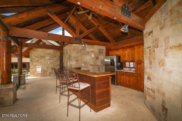 kitchen featuring stainless steel refrigerator with ice dispenser, a kitchen breakfast bar, kitchen peninsula, high vaulted ceiling, and beam ceiling