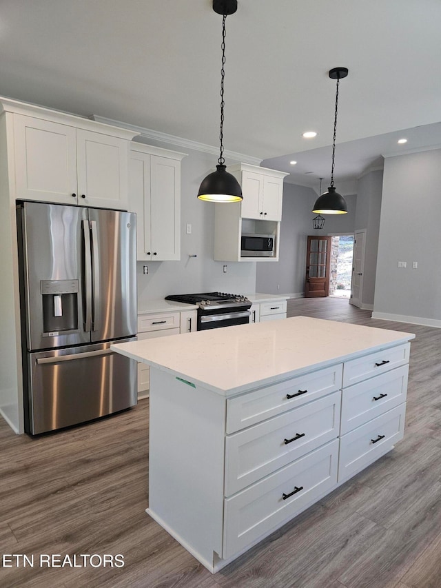 kitchen with decorative light fixtures, appliances with stainless steel finishes, hardwood / wood-style floors, and white cabinetry