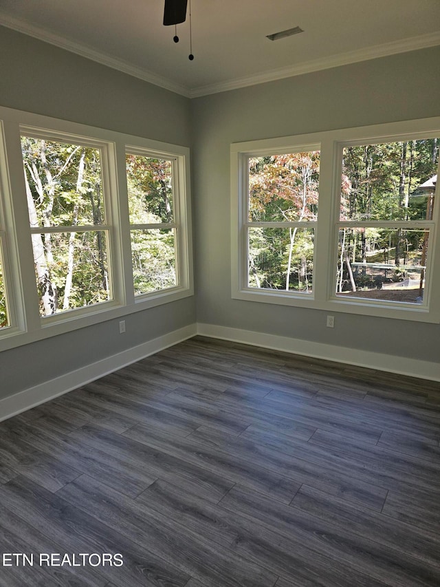 empty room featuring ceiling fan, dark hardwood / wood-style floors, crown molding, and a wealth of natural light