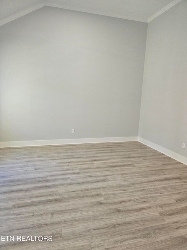 unfurnished room featuring light wood-type flooring, ornamental molding, and lofted ceiling