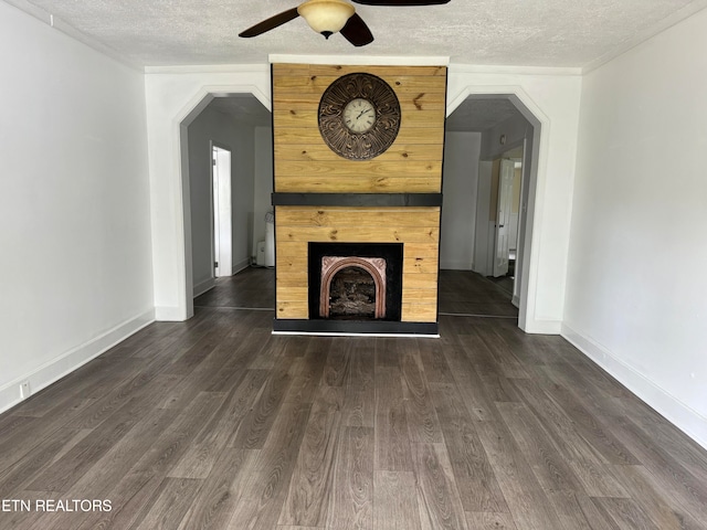 unfurnished living room featuring a fireplace, ceiling fan, a textured ceiling, and dark hardwood / wood-style floors