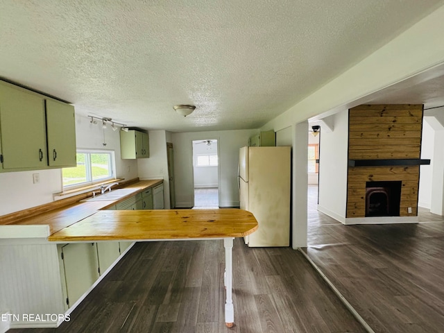 kitchen with dark wood-type flooring, a fireplace, wooden walls, and white refrigerator