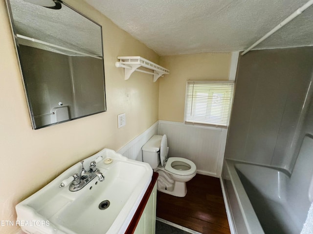 full bathroom with tub / shower combination, a textured ceiling, hardwood / wood-style flooring, toilet, and vanity