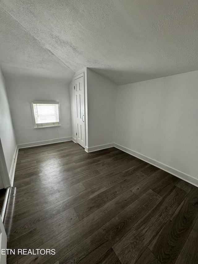 bonus room with dark wood-type flooring, a textured ceiling, and lofted ceiling