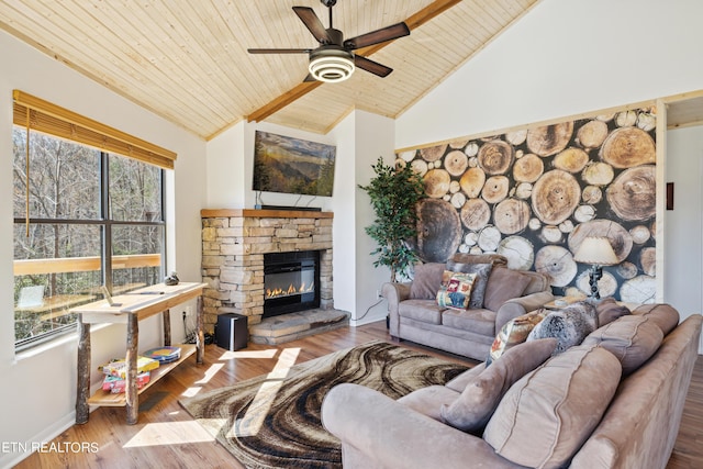 living room with wood ceiling, a stone fireplace, ceiling fan, high vaulted ceiling, and light hardwood / wood-style flooring