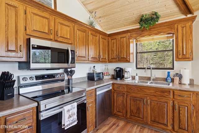 kitchen with appliances with stainless steel finishes, lofted ceiling, wood ceiling, light hardwood / wood-style floors, and sink