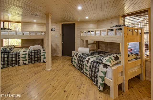 bedroom featuring light wood-type flooring, wood ceiling, and wooden walls