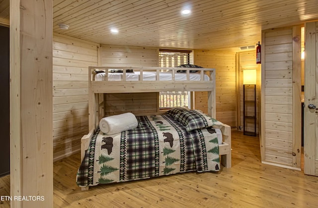 bedroom with wooden ceiling, light hardwood / wood-style floors, and wooden walls