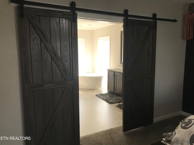 hallway with a barn door, carpet floors, and crown molding