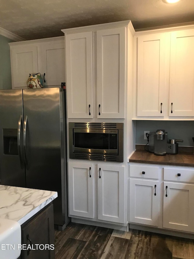 kitchen with dark hardwood / wood-style floors, light stone countertops, crown molding, stainless steel appliances, and white cabinetry