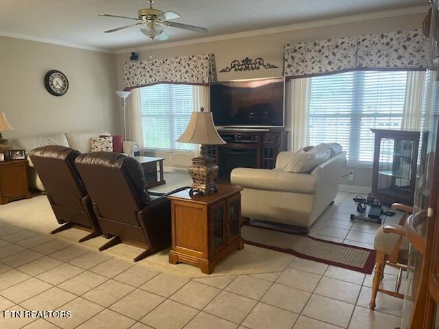 living room with ceiling fan, ornamental molding, and light tile flooring