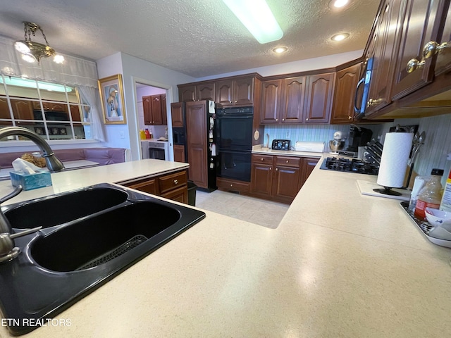 kitchen featuring black appliances, a textured ceiling, sink, and dark brown cabinetry