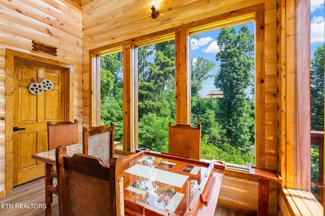 dining space with log walls and hardwood / wood-style flooring