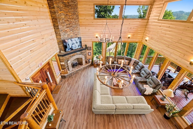 living room featuring high vaulted ceiling, a notable chandelier, hardwood / wood-style floors, and wood walls