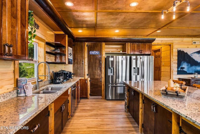 kitchen featuring light stone countertops, sink, wooden walls, and light wood-type flooring