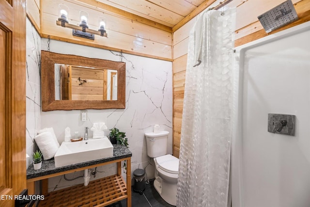 bathroom with tile floors, sink, toilet, and tile walls