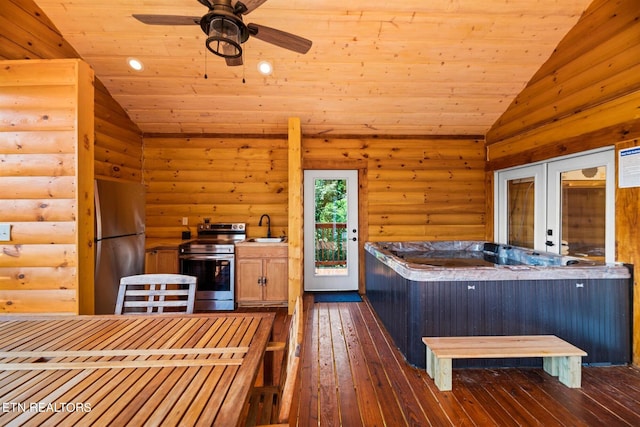 interior space with vaulted ceiling, appliances with stainless steel finishes, rustic walls, and dark wood-type flooring