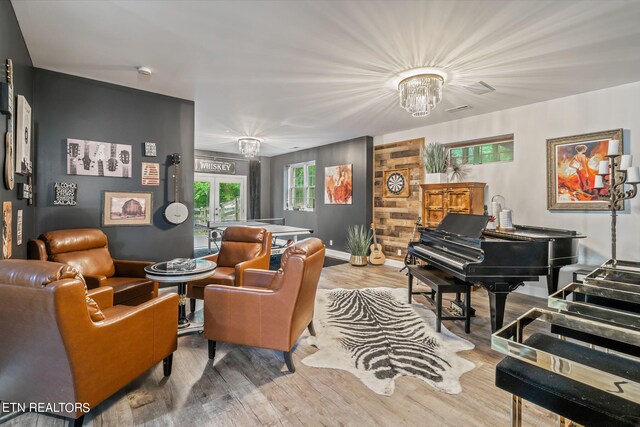 living room with an inviting chandelier, wooden walls, and light hardwood / wood-style flooring