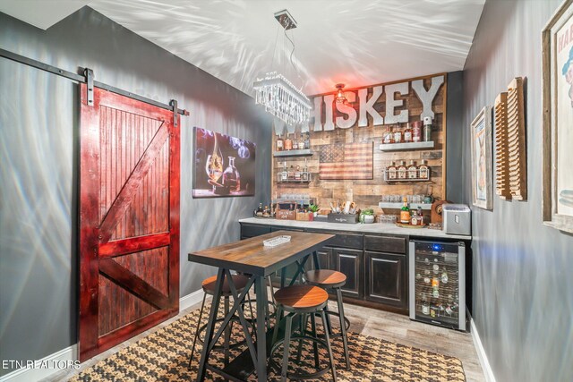 bar with beverage cooler, a barn door, and light wood-type flooring