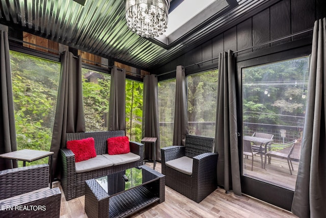 sunroom with a wealth of natural light, vaulted ceiling, and a notable chandelier