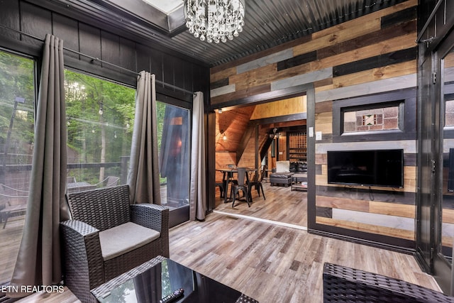 interior space featuring wood-type flooring, wooden walls, a chandelier, and a fireplace